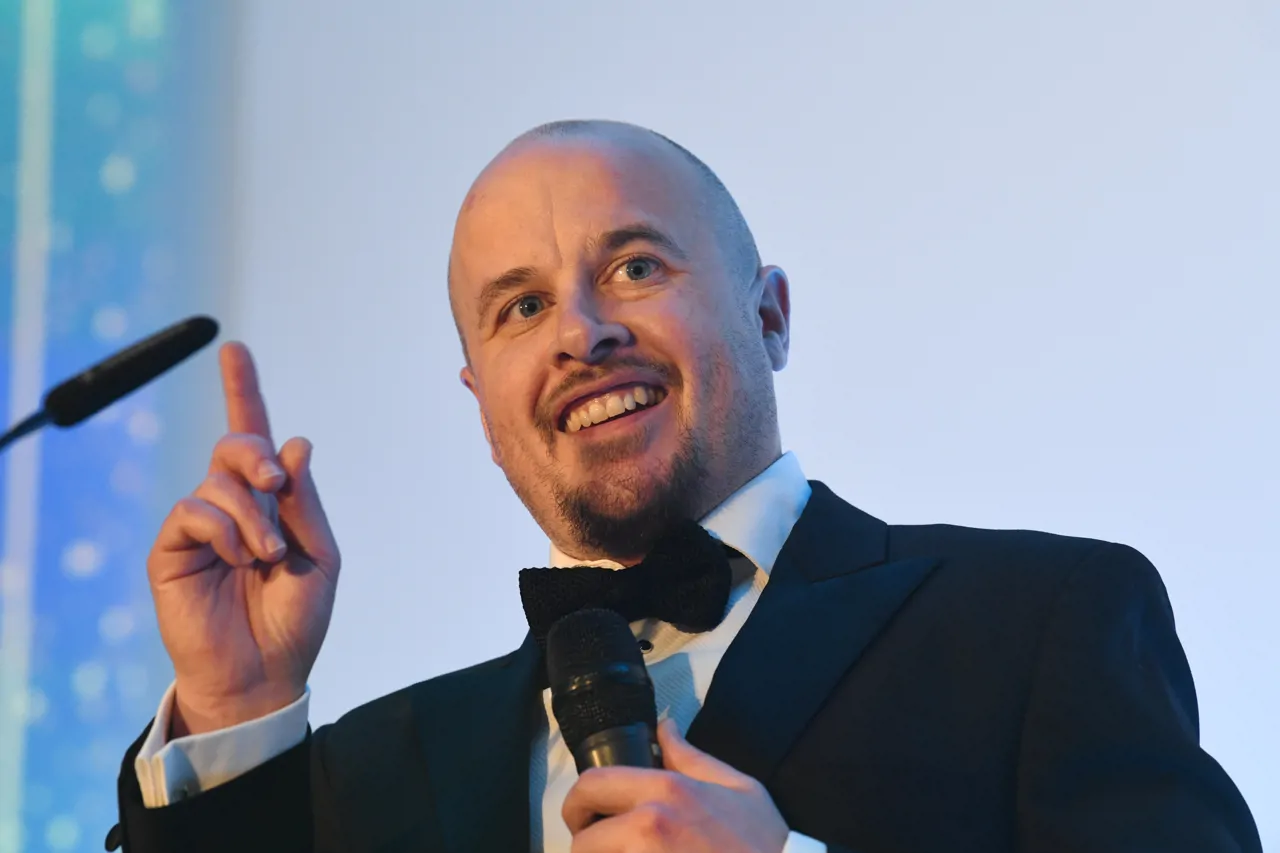 Man making a speech on stage with microphone in hand