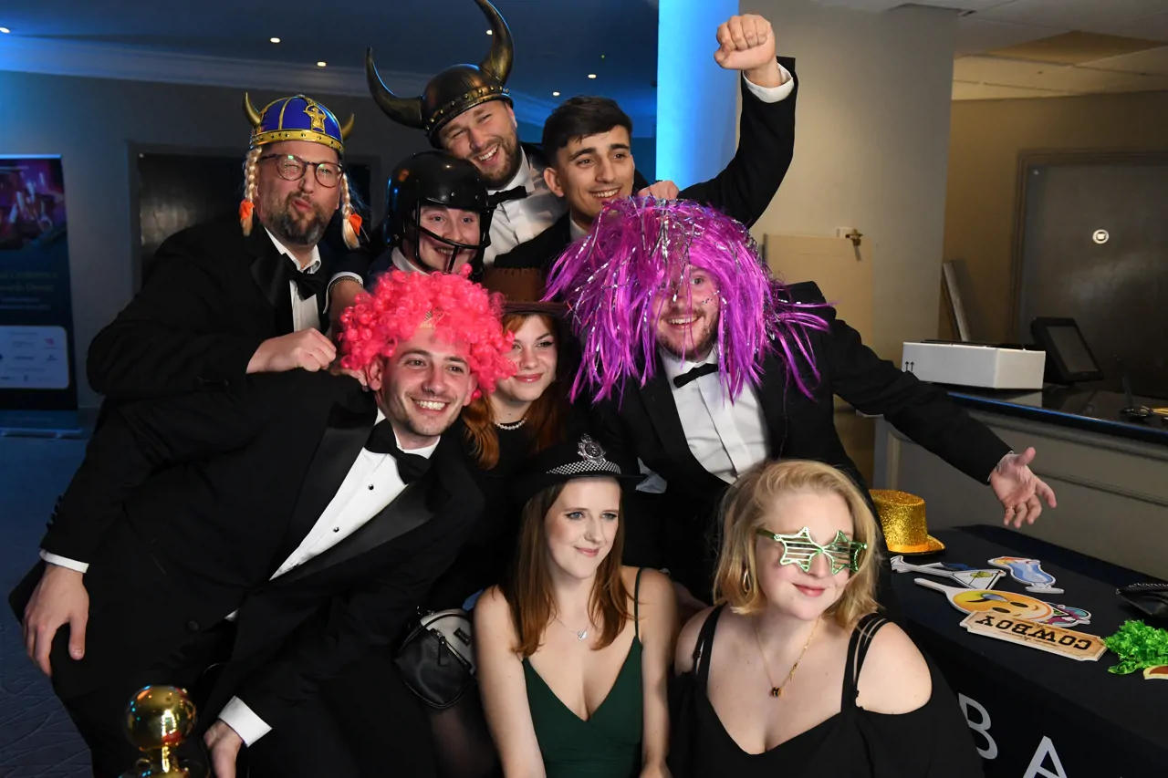 Group of employees at a awards conference posing with fancy dress props