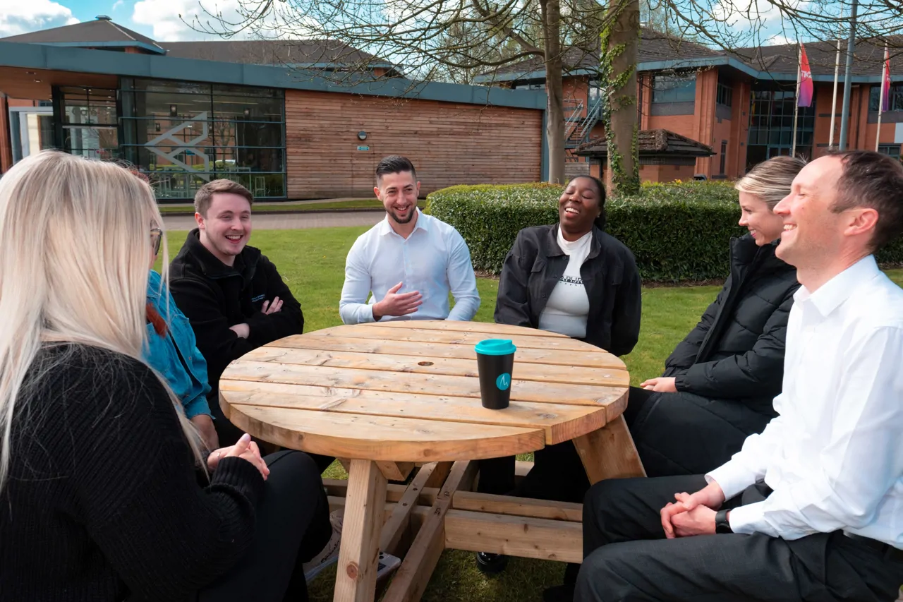 Team sat outside on a picnic bench laughing together